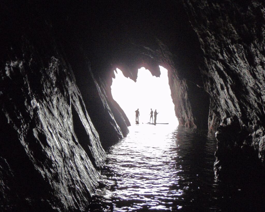 Stand Up Paddlers from a Sea Cave